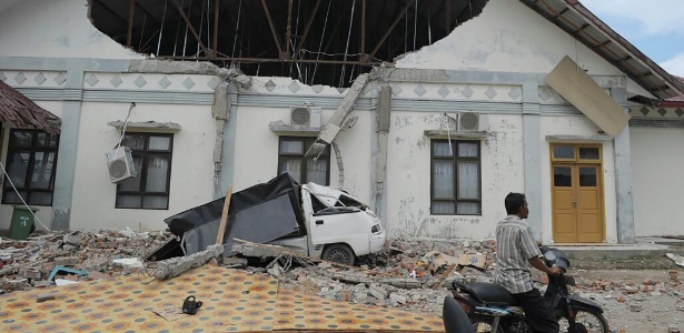 7dez2016-homem-passa-diante-de-hospital-destruido-pelo-terremoto-em-pidie-jaya-na-provincia-de-aceh-indonesia-1481105142211_615x300