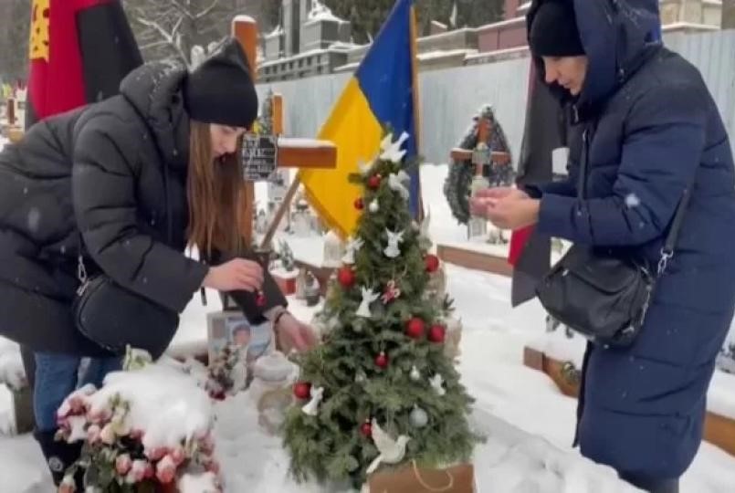 Viúva e mãe de soldado ucraniano decoram túmulo para o Natal